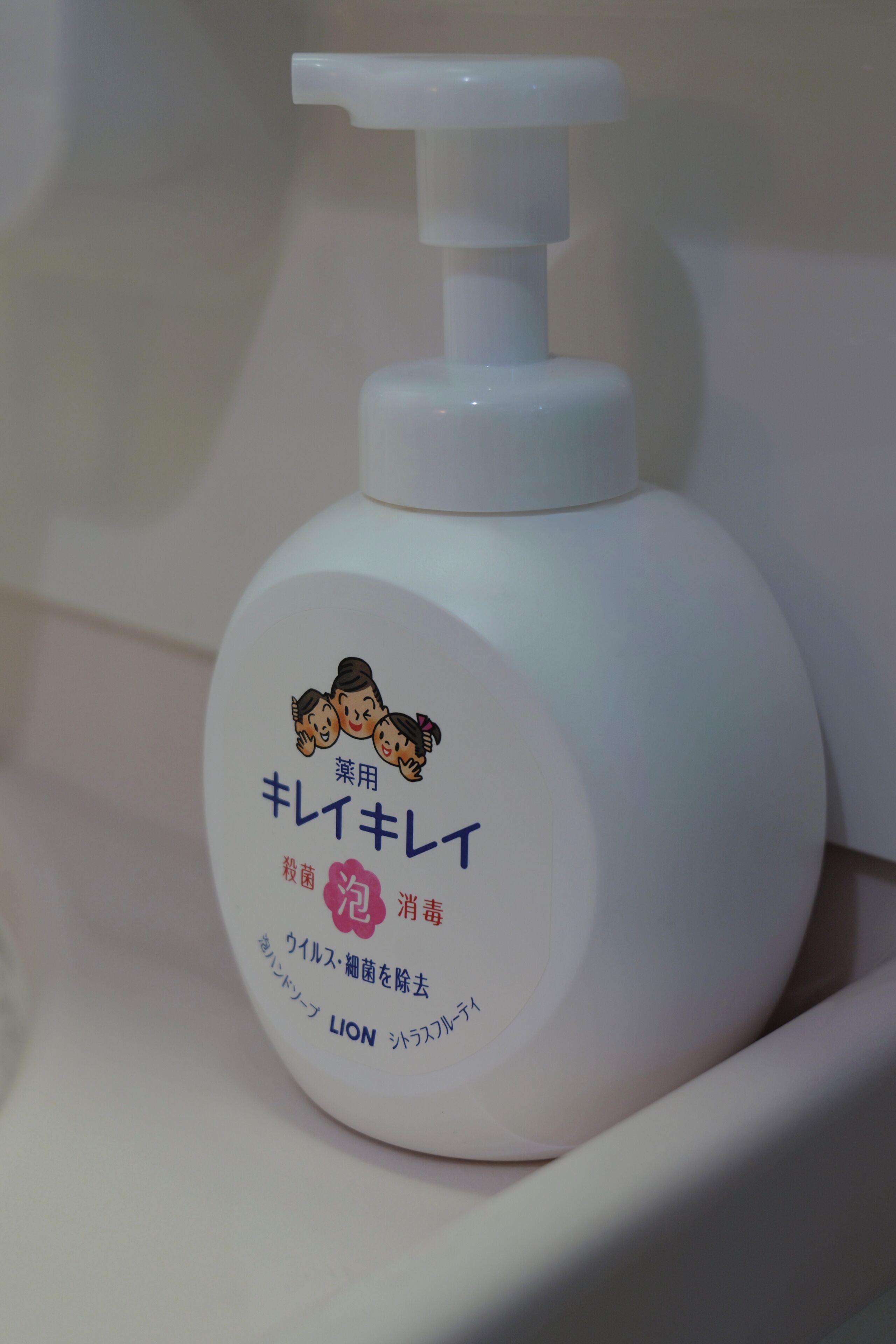 A white bottle with a pump dispenser, featuring Japanese text and a cartoon character.