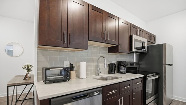 Una cocina moderna con armarios de madera oscura, electrodomésticos de acero inoxidable y un salpicadero de azulejos.