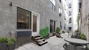 Un patio con mesas al aire libre, una escalera y plantas en macetas.