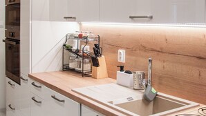 Una cocina moderna con armarios blancos, una encimera de madera y electrodomésticos de acero inoxidable.