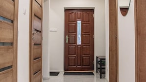 Un pasillo con puertas de madera, un espejo y suelo de baldosas.