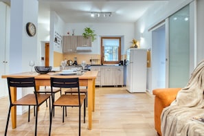A modern kitchen with a dining table, chairs, and a refrigerator.