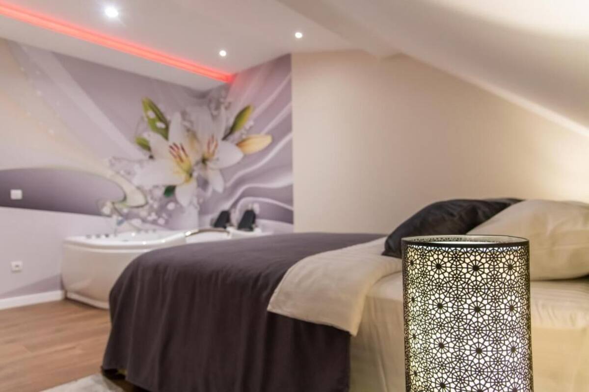 Un dormitorio moderno con cama, mesita de noche, decoración de pared y lámpara de pie.