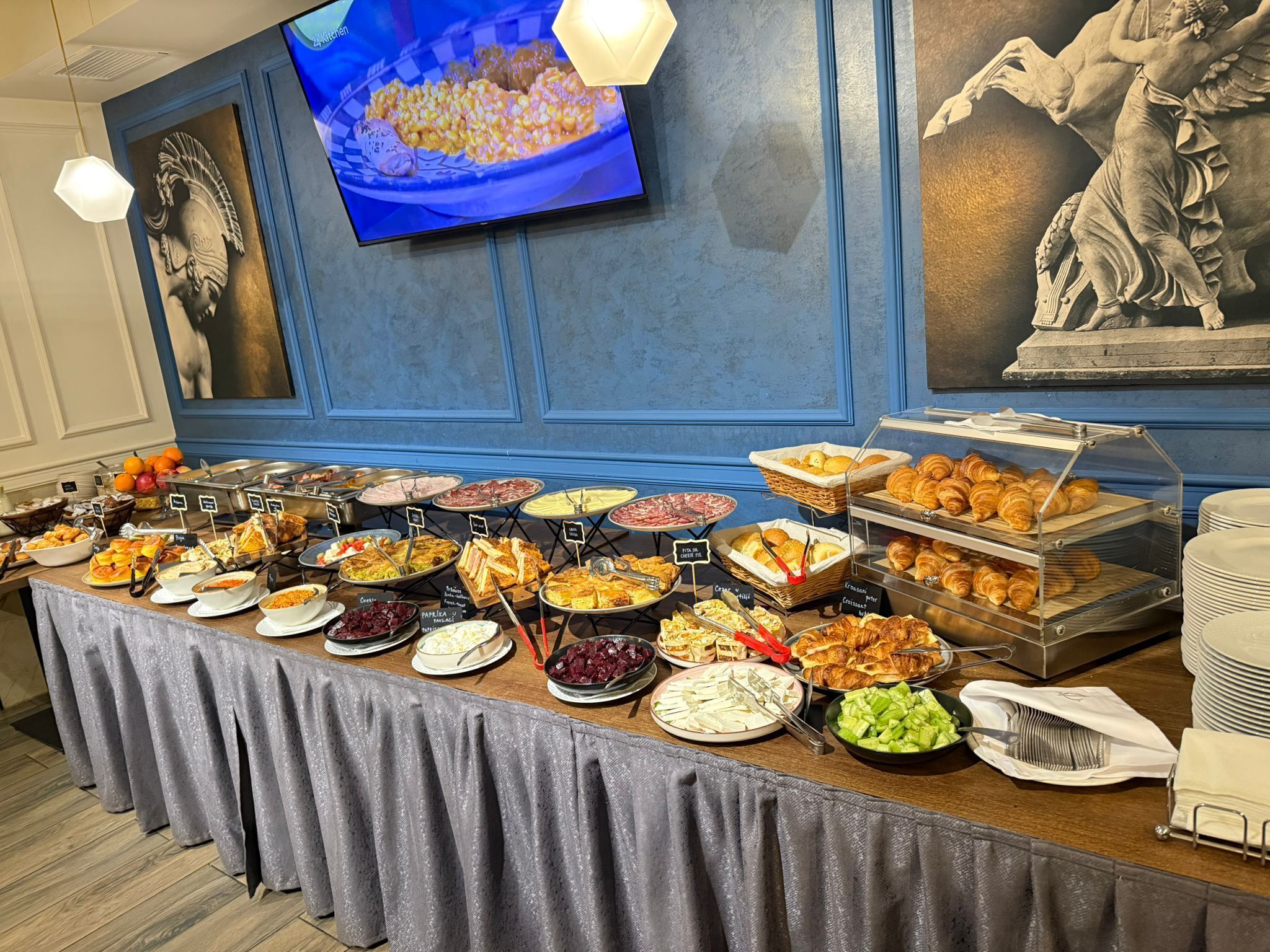 Un buffet proposant une variété de plats, avec un écran de télévision en arrière-plan.