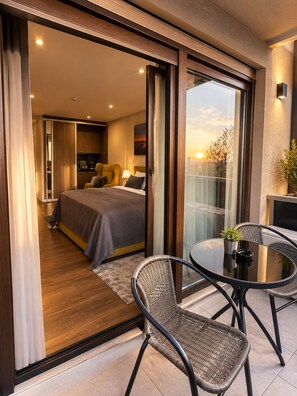 Ein modernes Hotelzimmer mit Balkon, einem Bett, einem Esstisch und einem Stuhl.