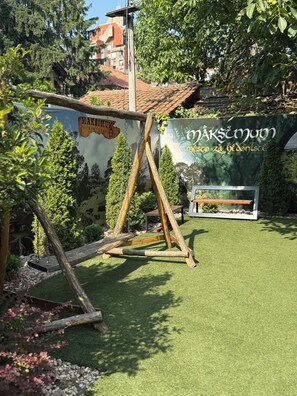 Un parc infantil de fusta en un jardí amb un mural al fons.