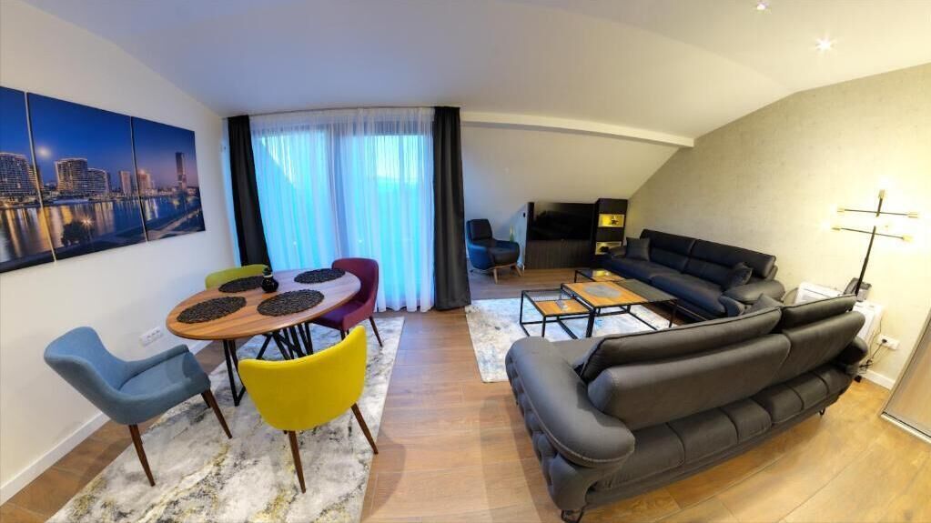 Een moderne woonkamer met een bank, een eettafel met stoelen en een televisie.