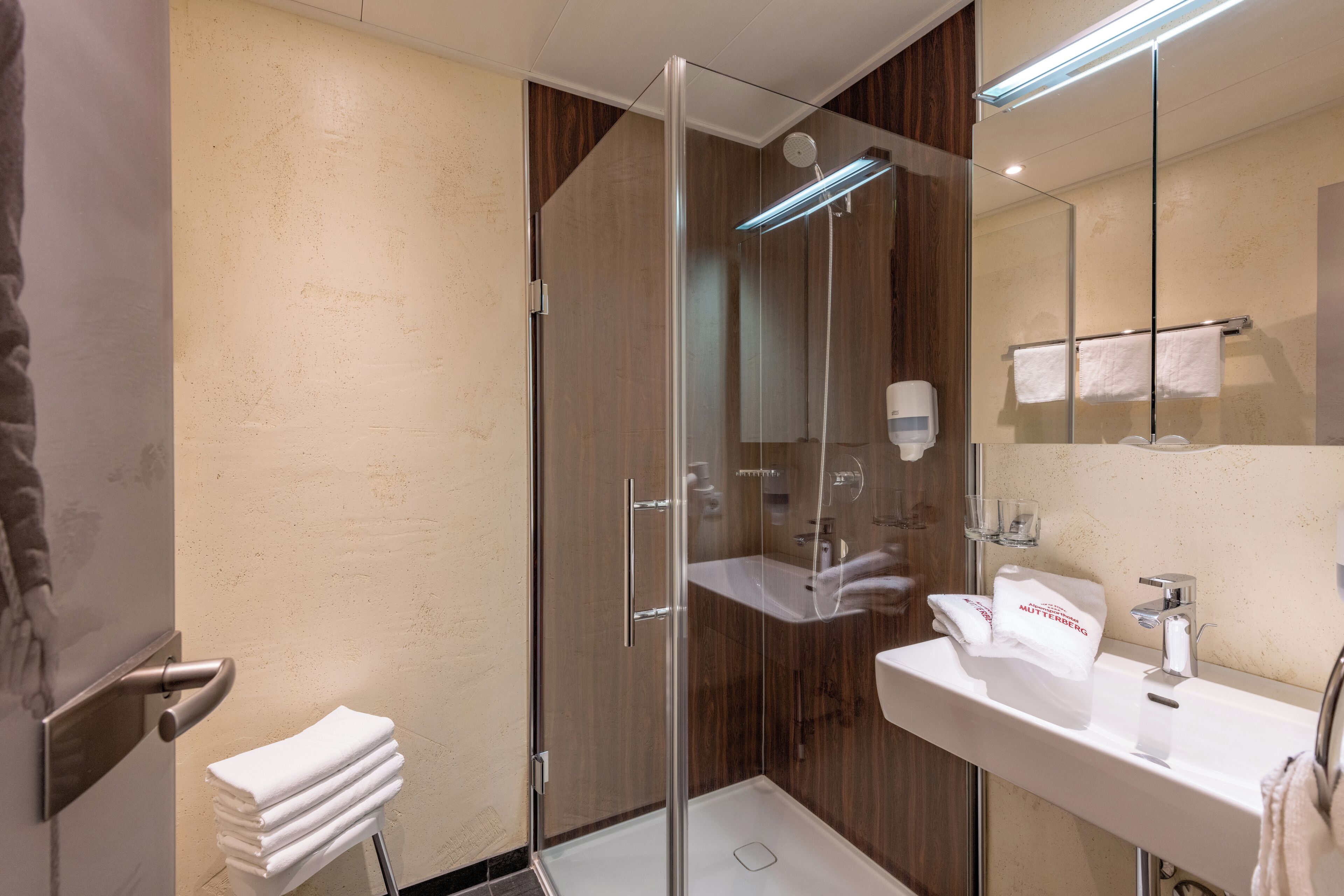 Une salle de bain moderne avec une douche à parois de verre, un lavabo et un porte-serviettes.