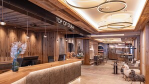 A reception area with a wooden reception desk, a sign reading "TOP OF STUBAI", and a seating area with tables and chairs. - Alpensporthotel Mutterberg (Neustift Im Stubaital)