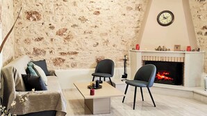 Una sala de estar acogedora con pared de piedra, chimenea, sofá, dos sillones y una mesa de centro.
