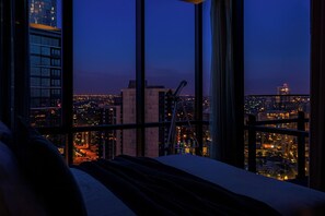 Une chambre située dans un immeuble de grande hauteur, offrant une vue sur la ville, dotée de grandes fenêtres et d’un télescope.