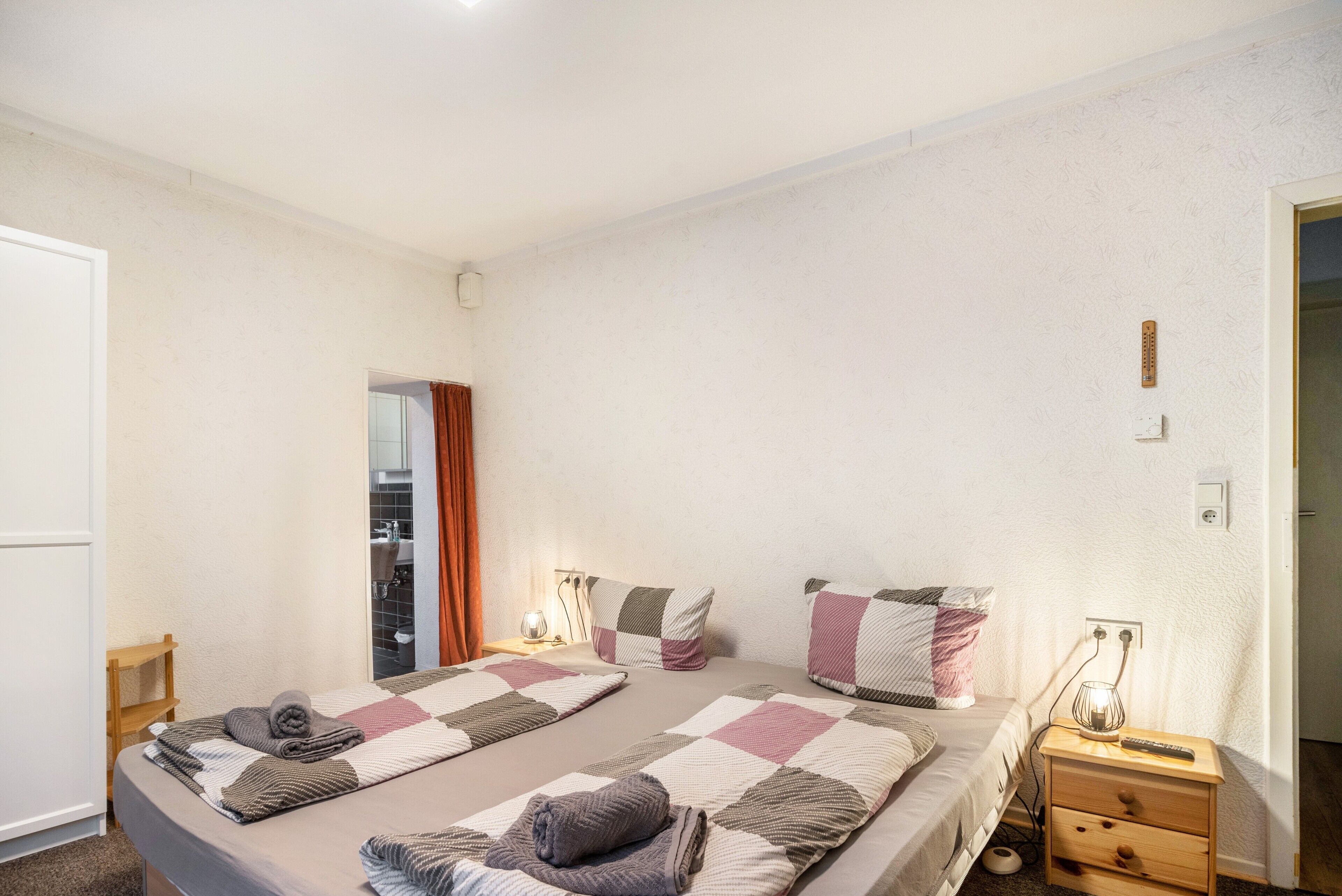 Een slaapkamer met twee bedden, een nachtkastje met een lamp en een kledingkast.