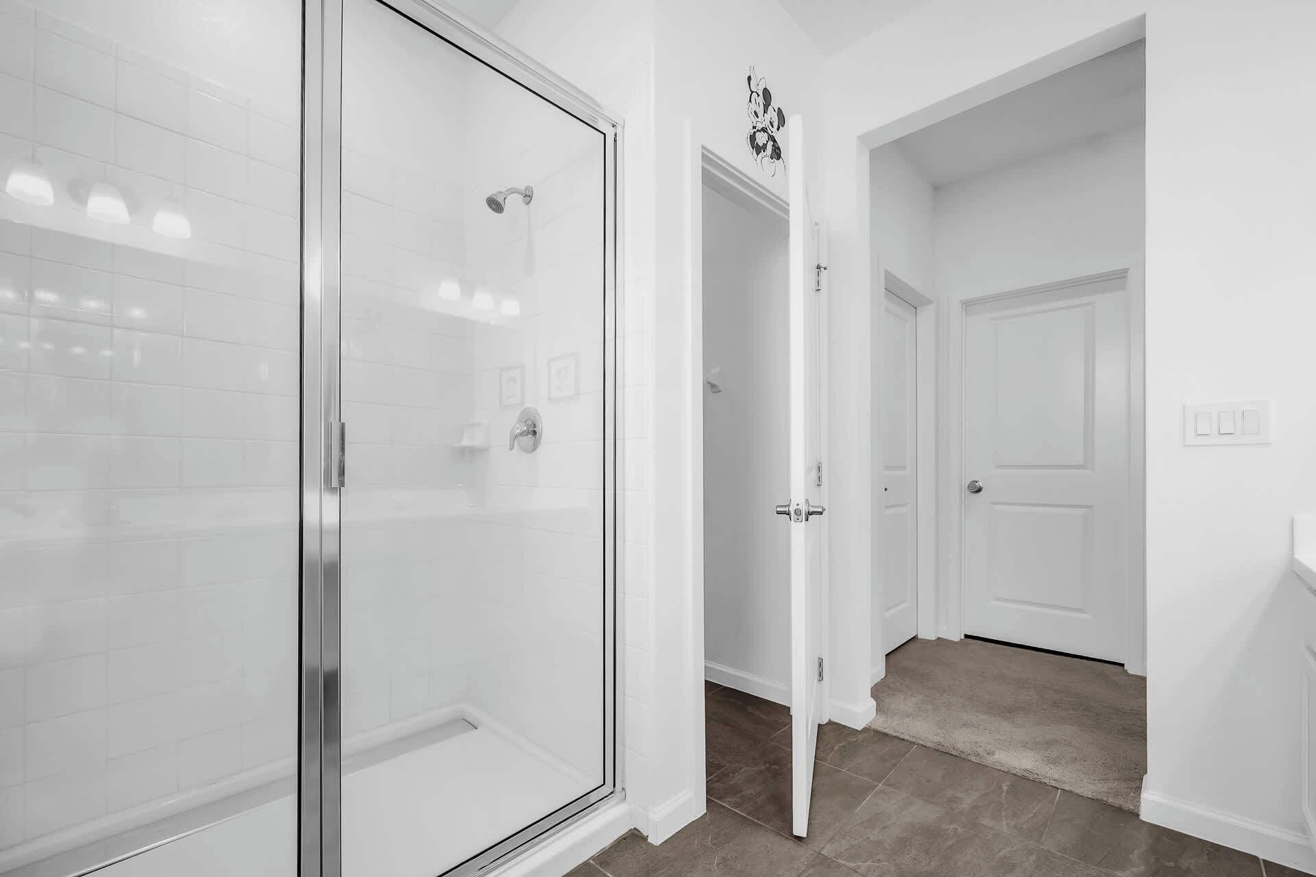 A modern bathroom with a glass shower enclosure, white tiled walls, and a visible showerhead.