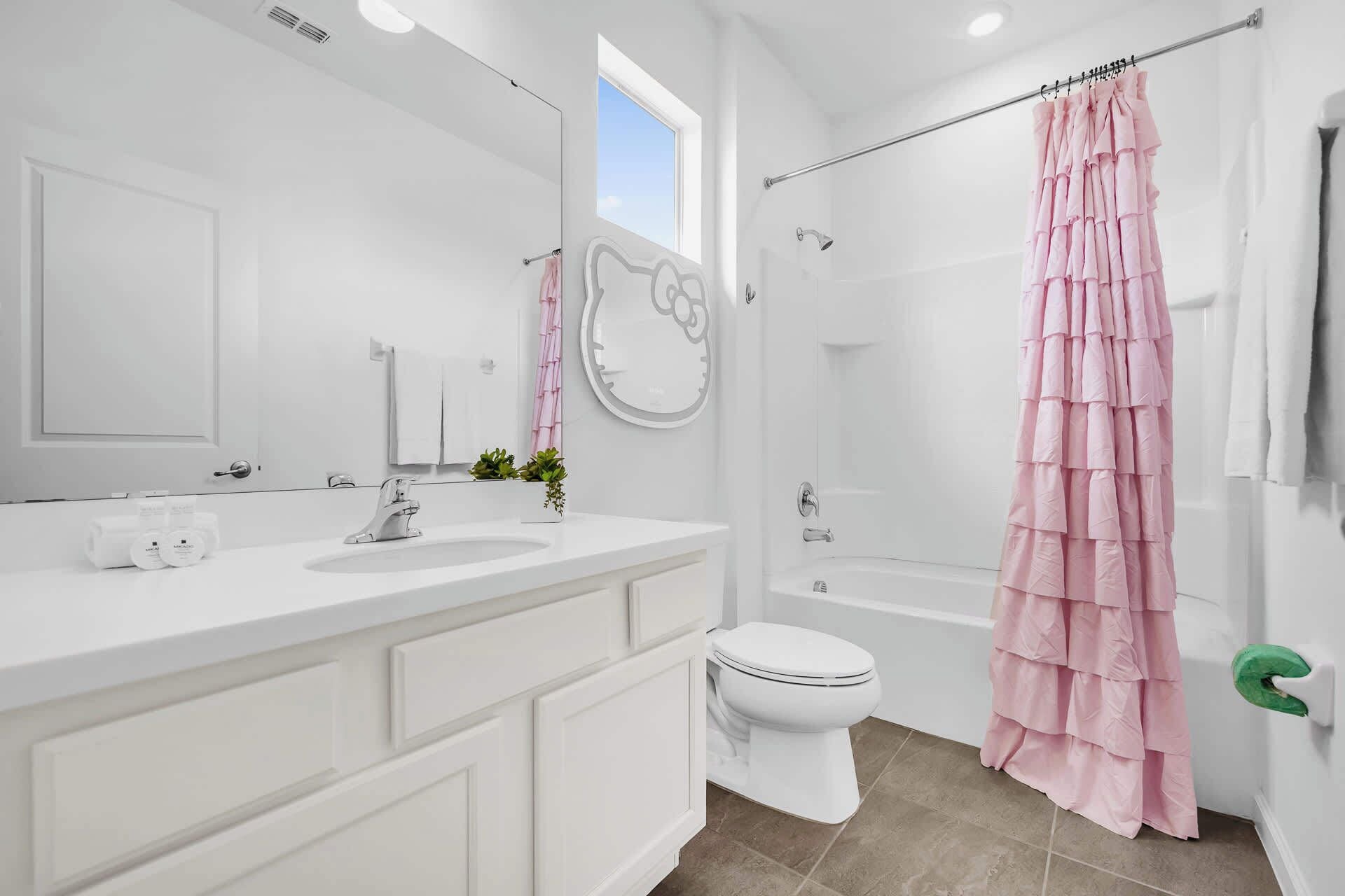 A modern bathroom with a white vanity, a toilet, and a shower with a pink curtain.