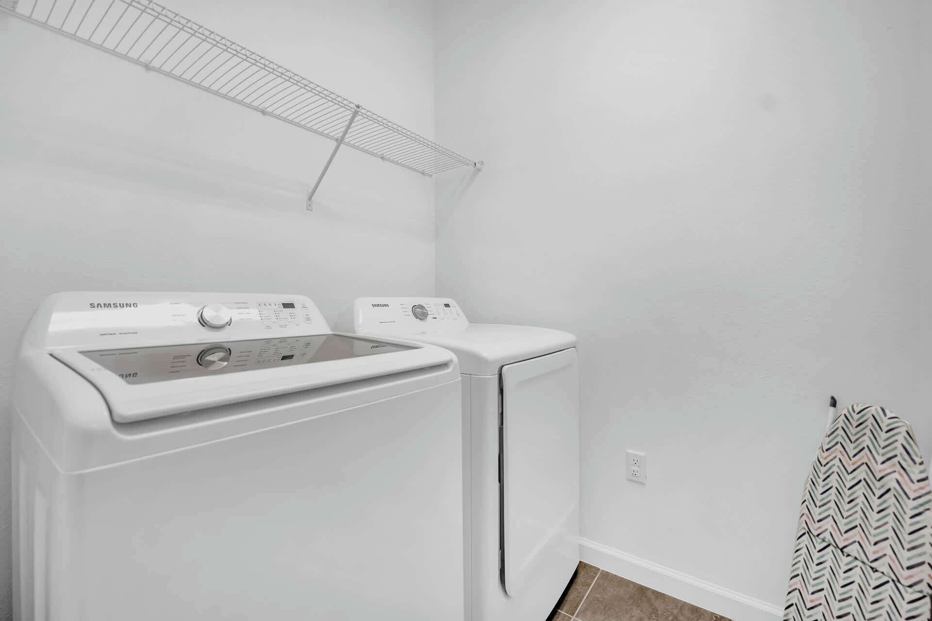 Una sala de bugaderia amb dues rentadores Samsung blanques i un escorrador.