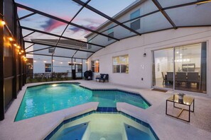 A swimming pool with a glass ceiling, a patio area with seating, and a view of the interior. - Upstay Vibrant Home w Themed Rooms Pool Games (Kissimmee)
