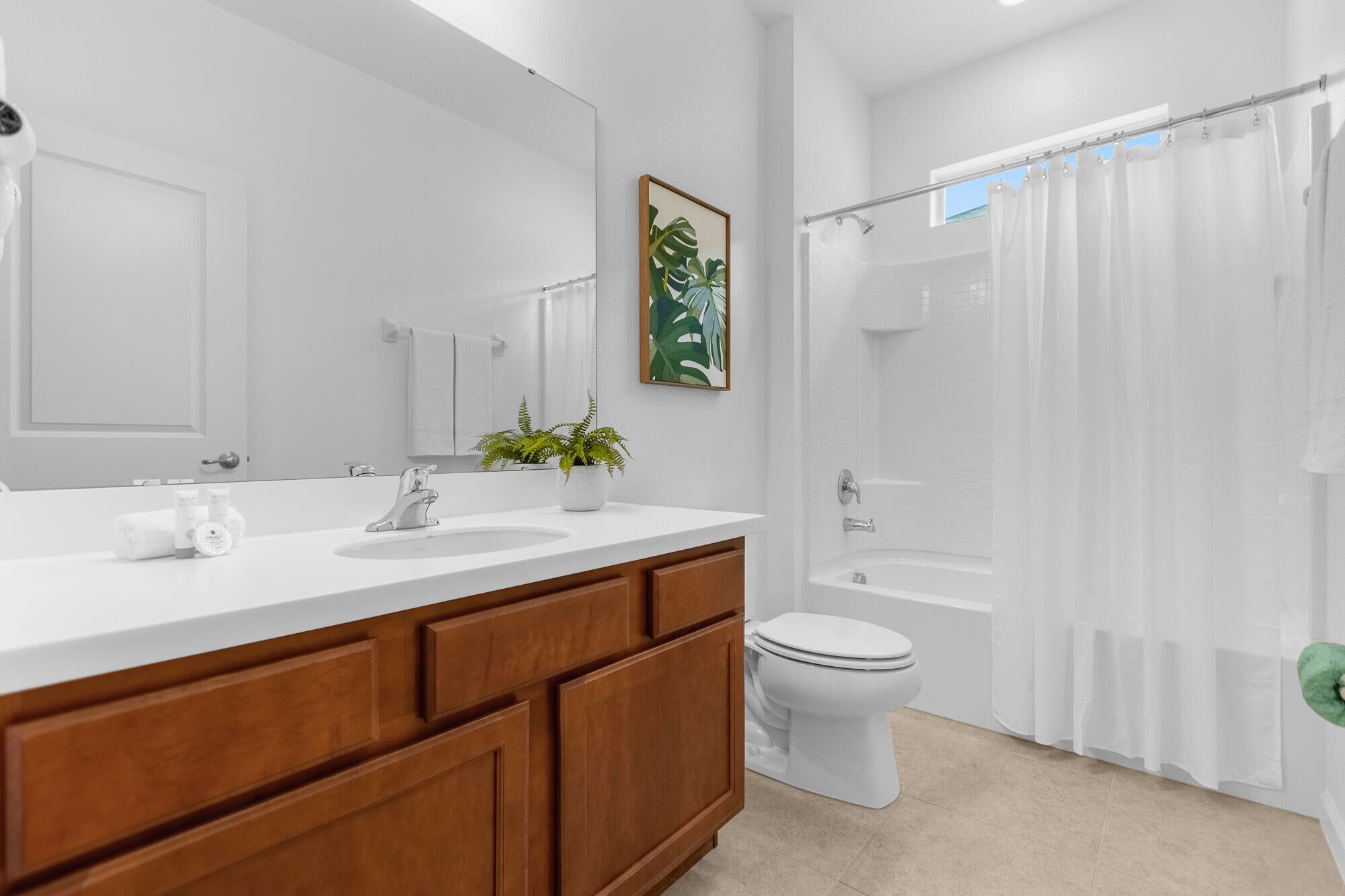 Une salle de bain moderne avec un meuble-lavabo blanc, un grand miroir, une douche avec une porte en verre et des toilettes.