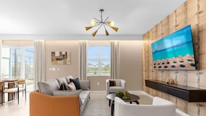 Una sala de estar moderna con un sofá, sillones, una mesa de centro y un televisor montado en una pared de madera.
