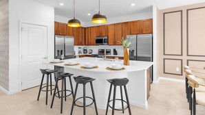 Una cocina moderna con armarios de madera, electrodomésticos de acero inoxidable y una isla central con taburetes de bar.
