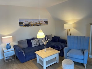 A living room with a sofa, a coffee table, a chair, a lamp, and a painting on the wall.