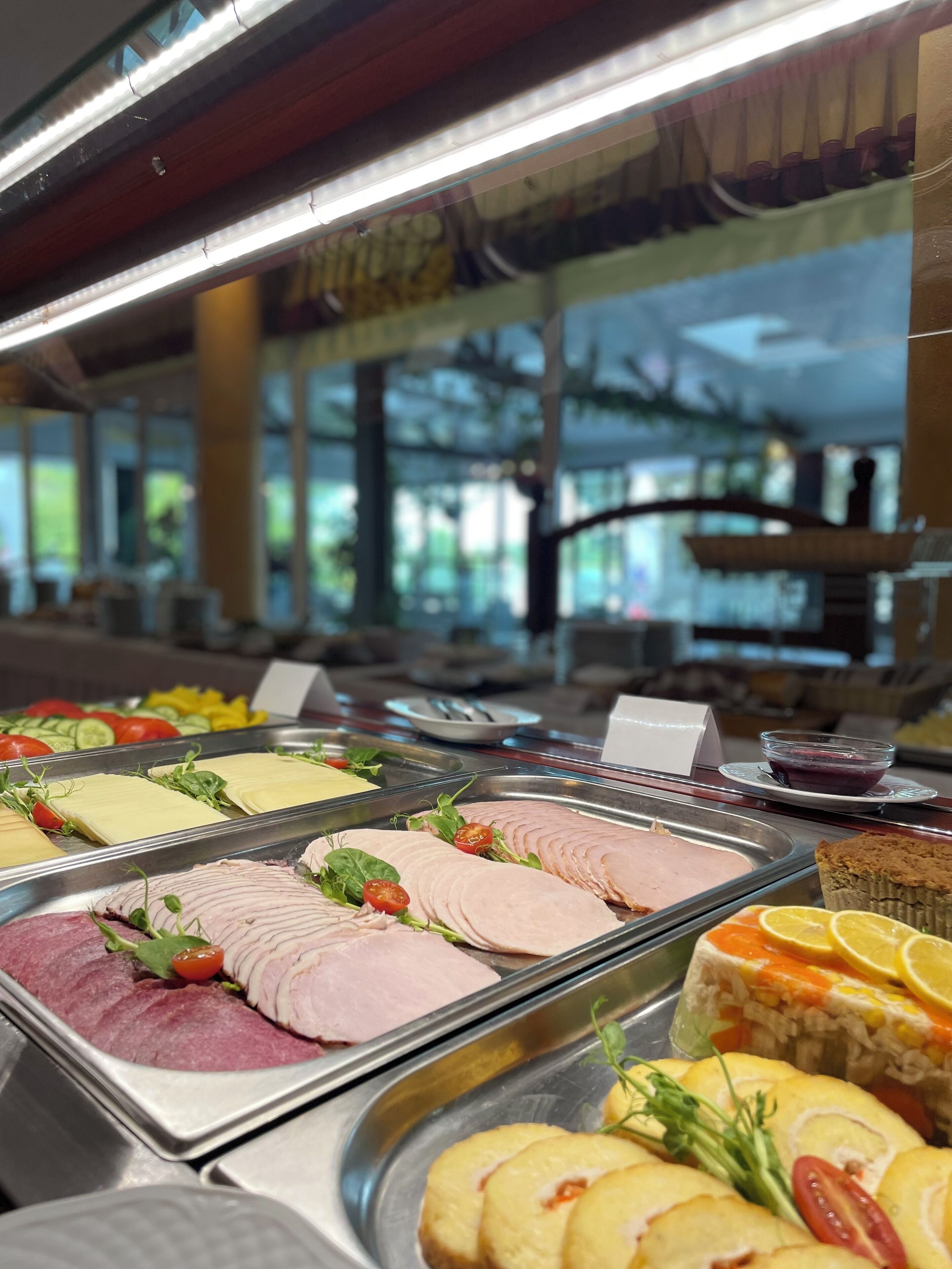 Un bufé con diversas opciones de comida, incluyendo embutidos, quesos y verduras.