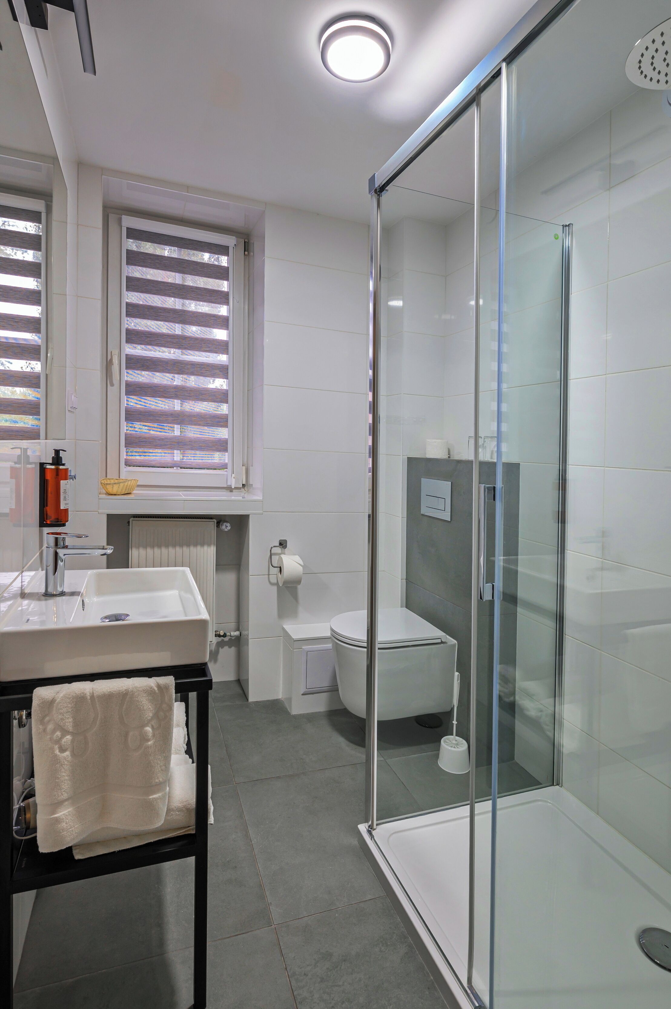 Un baño moderno con cabina de ducha de vidrio, un lavabo con toalla y un inodoro.