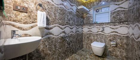 A bathroom with a marble sink, a toilet, and a shower.