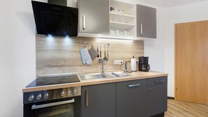 Una cuina compacta amb forn encastrat, microones, rentamics i cafetera.