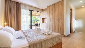 Ein modernes Hotelzimmer mit einem großen Bett, einem Laptop auf dem Bett und Blick ins Freie durch das Fenster.