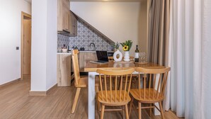 Eine moderne Küche mit Holzausstattung, einem Laptop auf der Arbeitsfläche und einem Essbereich mit Tisch und Stühlen.