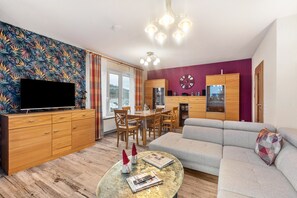 A living room with a sofa, a coffee table, a TV, and a dining area with chairs and a table. - Apartment Ruhrtal – Central Location in Bestwig, Supermarkets Nearby, Garden Access, Fiber Internet (Bestwig)