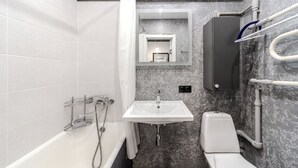 A bathroom with a bathtub, a sink, a toilet, and a shower curtain. - StudioMinsk Romanovskaya Sloboda 12 (Minsk)