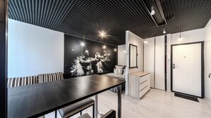 A modern room with a wooden dining table, a bench, a black and white mural, a wardrobe, and a door. - StudioMinsk Romanovskaya Sloboda 12 (Minsk)