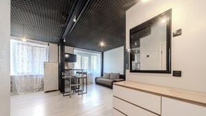 A modern living room with a wooden floor, a sofa, a dining area with a table and chairs, and a large mirror on the wall. - StudioMinsk Romanovskaya Sloboda 12 (Minsk)