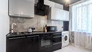 A modern kitchen with a built-in oven, microwave, and dishwasher. - StudioMinsk Romanovskaya Sloboda 12 (Minsk)