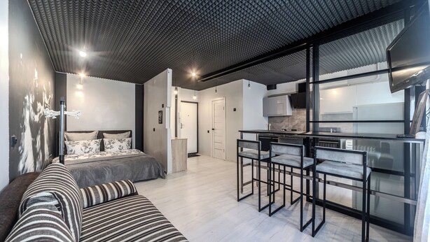 A modern apartment with a bed, a sofa, a dining area, and a kitchen. - StudioMinsk Romanovskaya Sloboda 12 (Minsk)