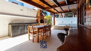 An outdoor dining area with a brick oven, wooden tables, and chairs. - 014D-Village Praia dos Carneiros III (Tamandaré)