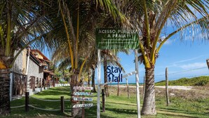 A signpost with directions and a 'Stay Hall' sign, indicating a beach access point and a hotel. - 014D-Village Praia dos Carneiros III (Tamandaré)