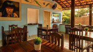 A restaurant with wooden tables and chairs, a wall-mounted fan, and a ceiling fan.