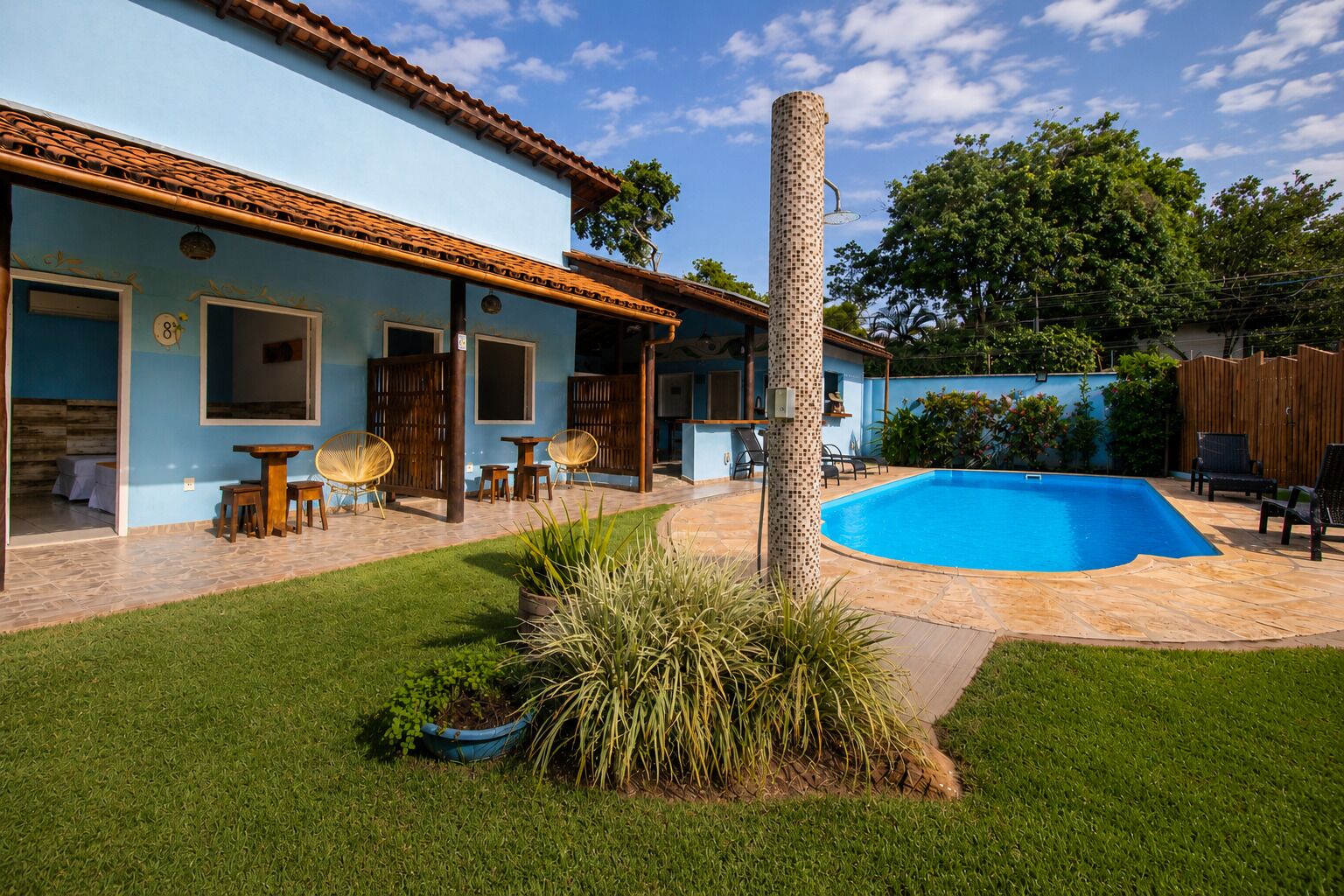 Una propiedad residencial con piscina, mobiliario de exterior y un césped bien cuidado.