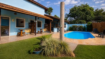 Una propiedad residencial con piscina, mobiliario de exterior y un césped bien cuidado.