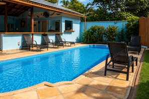 Piscina amb gandules i zona de pati coberta.