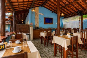 A restaurant with wooden tables and chairs, a blue wall, and a menu board.