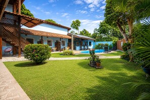 A two-story building with a swimming pool, a covered patio, and a well-maintained lawn.