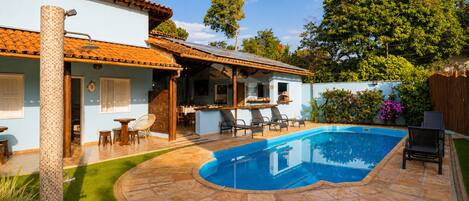 A residential property with a swimming pool, outdoor seating area, and a covered patio.