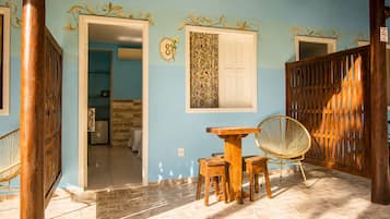 A room with a wooden table and chairs, a woven chair, a door with a number, and a patterned wall.