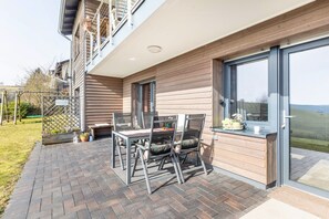 Un patio con mesa y sillas, una valla de madera y vistas al campo.