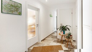 Un pasillo con un mapa en la pared, una puerta con vidrio esmerilado y una pequeña mesa con plantas.