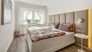 Un dormitorio moderno con una cama grande, mesita de noche y vistas al exterior.