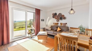 Una sala moderna con sofá, mesa de comedor y sillas, un ventanal con cortinas y decoración mural.